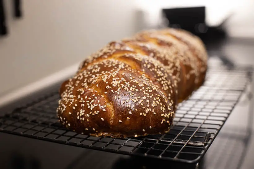sourdough challah with sesame seeds cooling on a wire rack