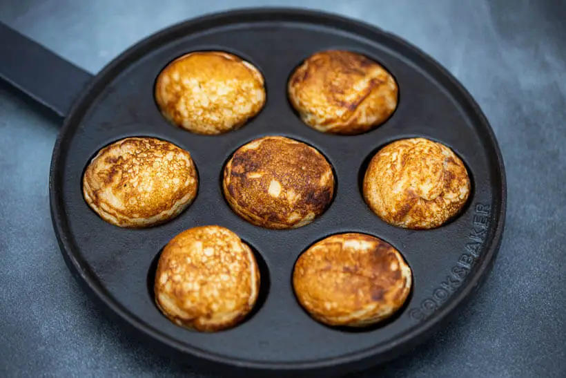Pan full of sourdough æbleskiver on a concrete floor seen from the side