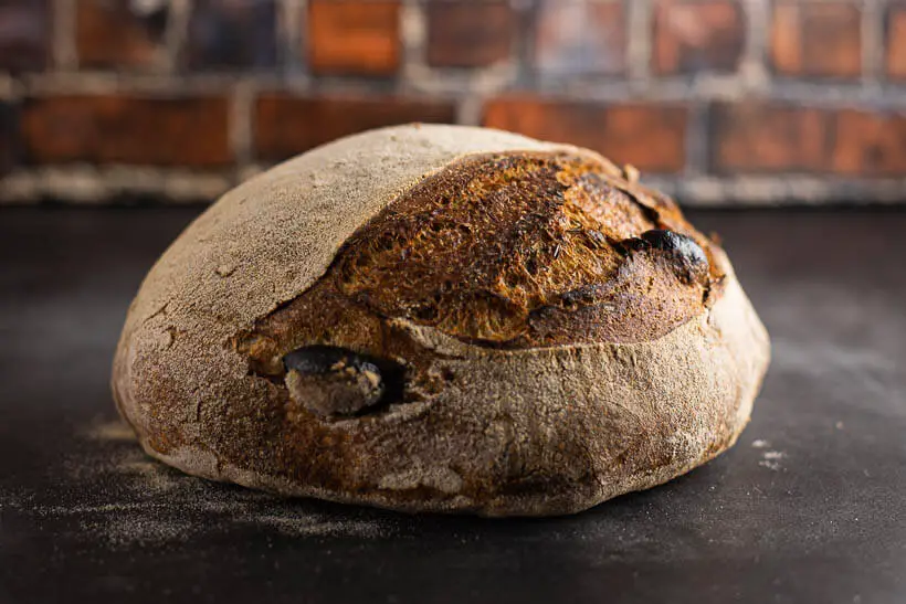 Sourdough olive bread on a concrete floor in front of a brick wall