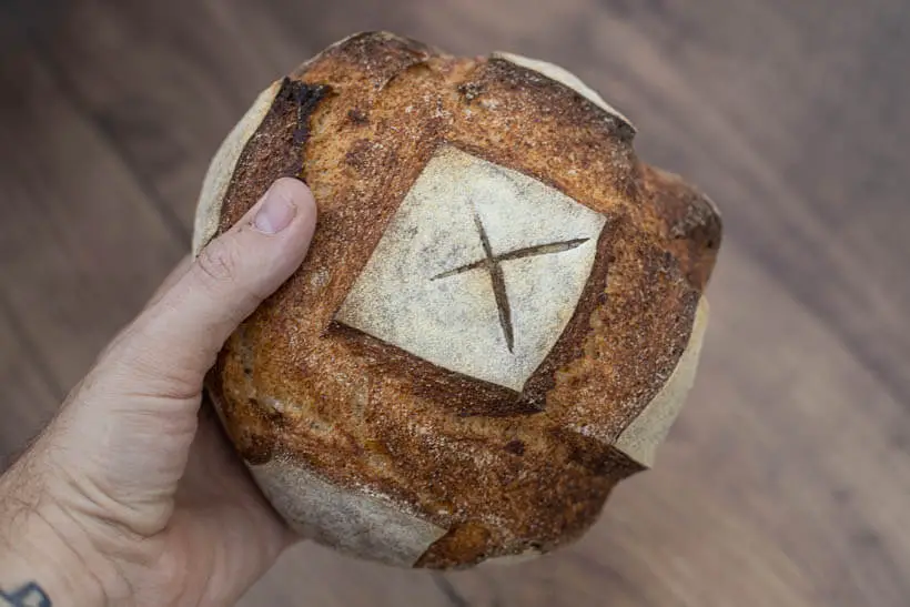 holding an artisan sourdough bread made using my own hands