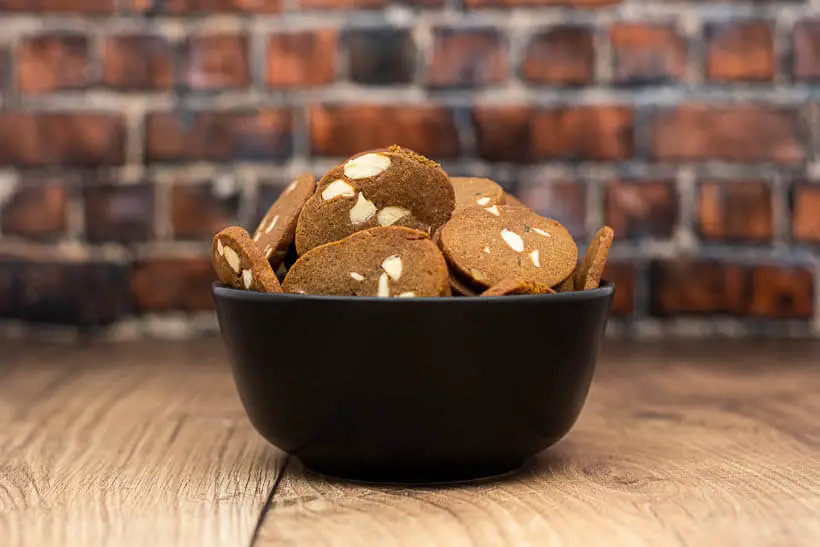 brunkager in a black bowl on a wooden floor in front of a brick wall. Perfect Danish Christmas cookies.