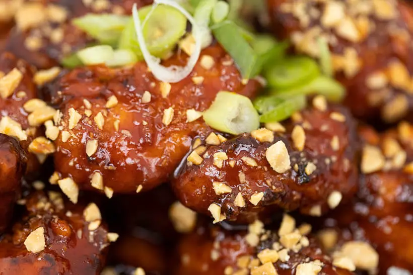 closeup of korean fried chicken with chopped salted peanuts