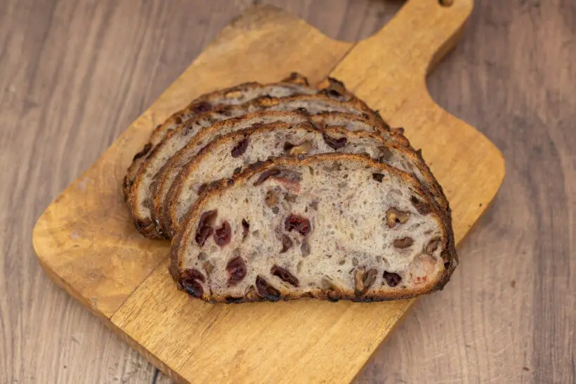 cross cut of this walnut cranberry sourdough bread with bourbon soaked cranberries and toasted walnuts in the crumb