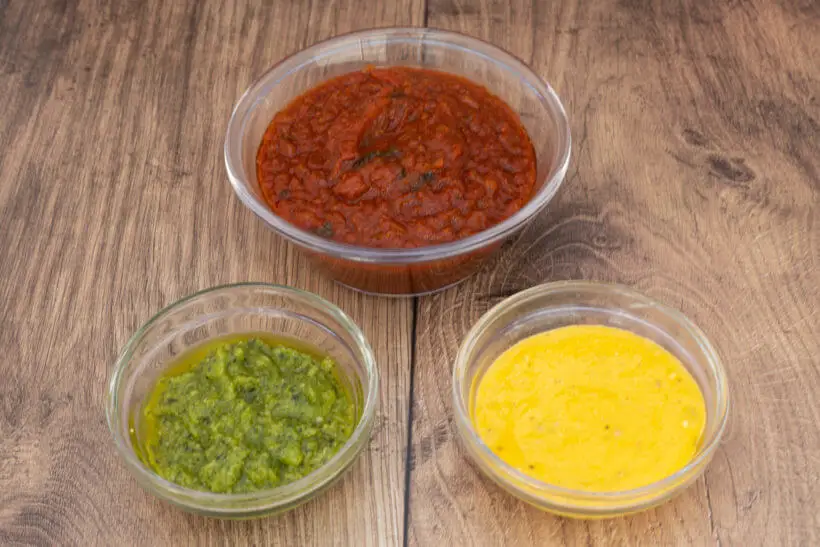 a stop light of sauces: red marinara sauce, green basil pesto and yellow Caesar sauce