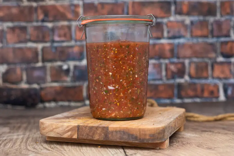 a jar of homemade salsa on a board