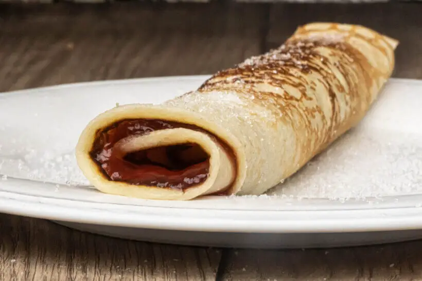 a sweet crêpe with strawberry jam and sugar on top