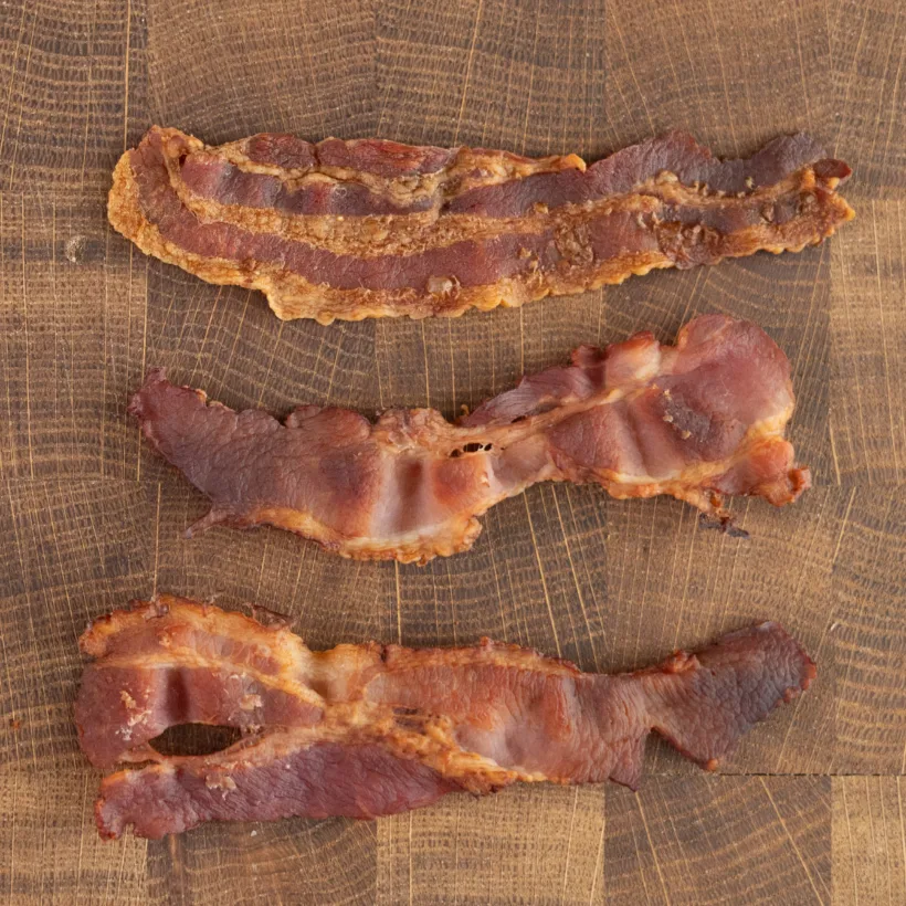 Thin strips of bacon baked in the oven with parchment paper