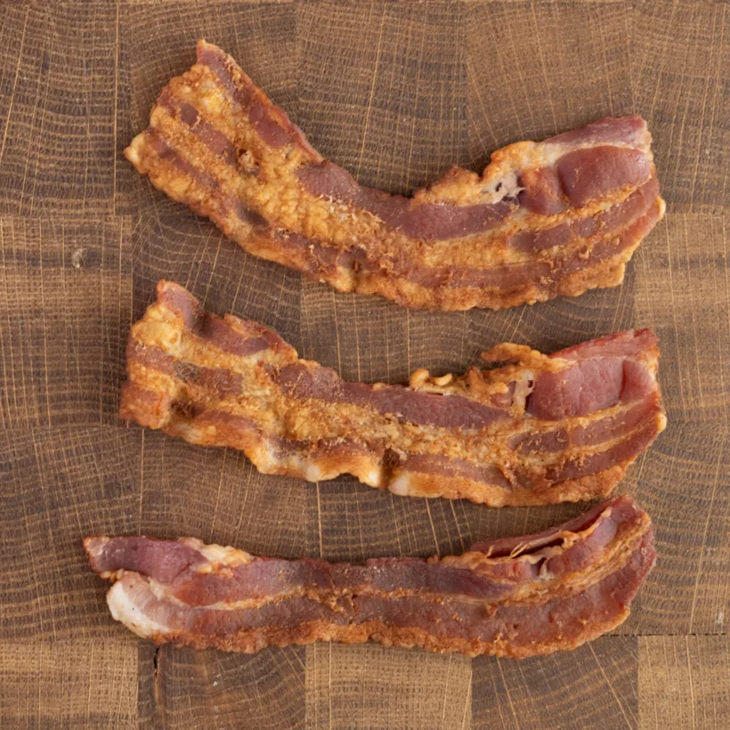 Thick strips of bacon cooked with water in the skillet